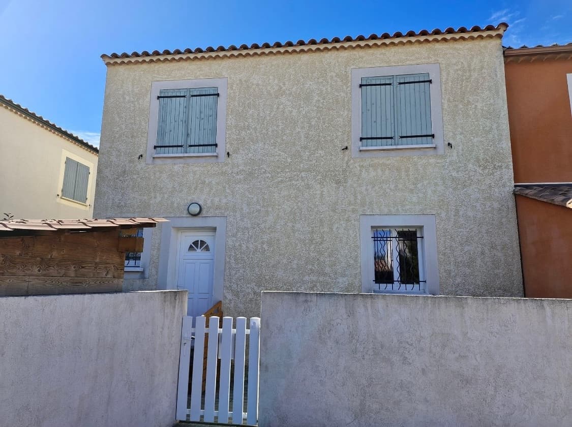 Façade extérieure de la Maison d'Assistantes Maternelles avec ses volets bleus et sa petite barrière blanche.
