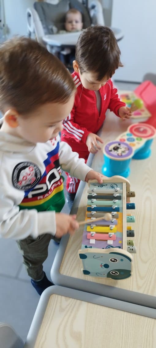 Des enfants jouent avec des instruments de musique colorés, dont un xylophone en bois, lors d'un moment d'éveil musical à la MAM.